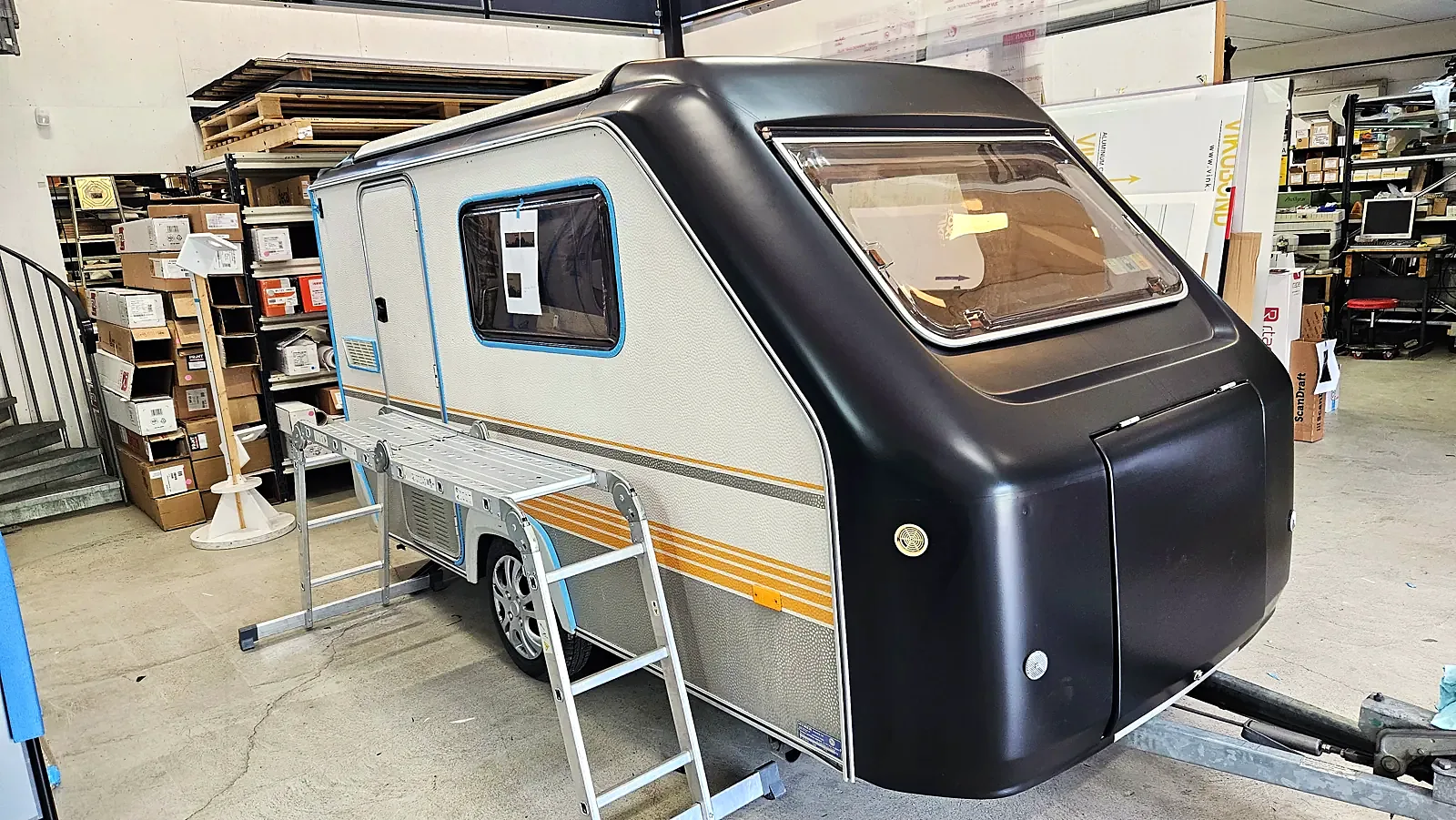 Campingvogna underveis i folieringen, med sort front og hvite sider
