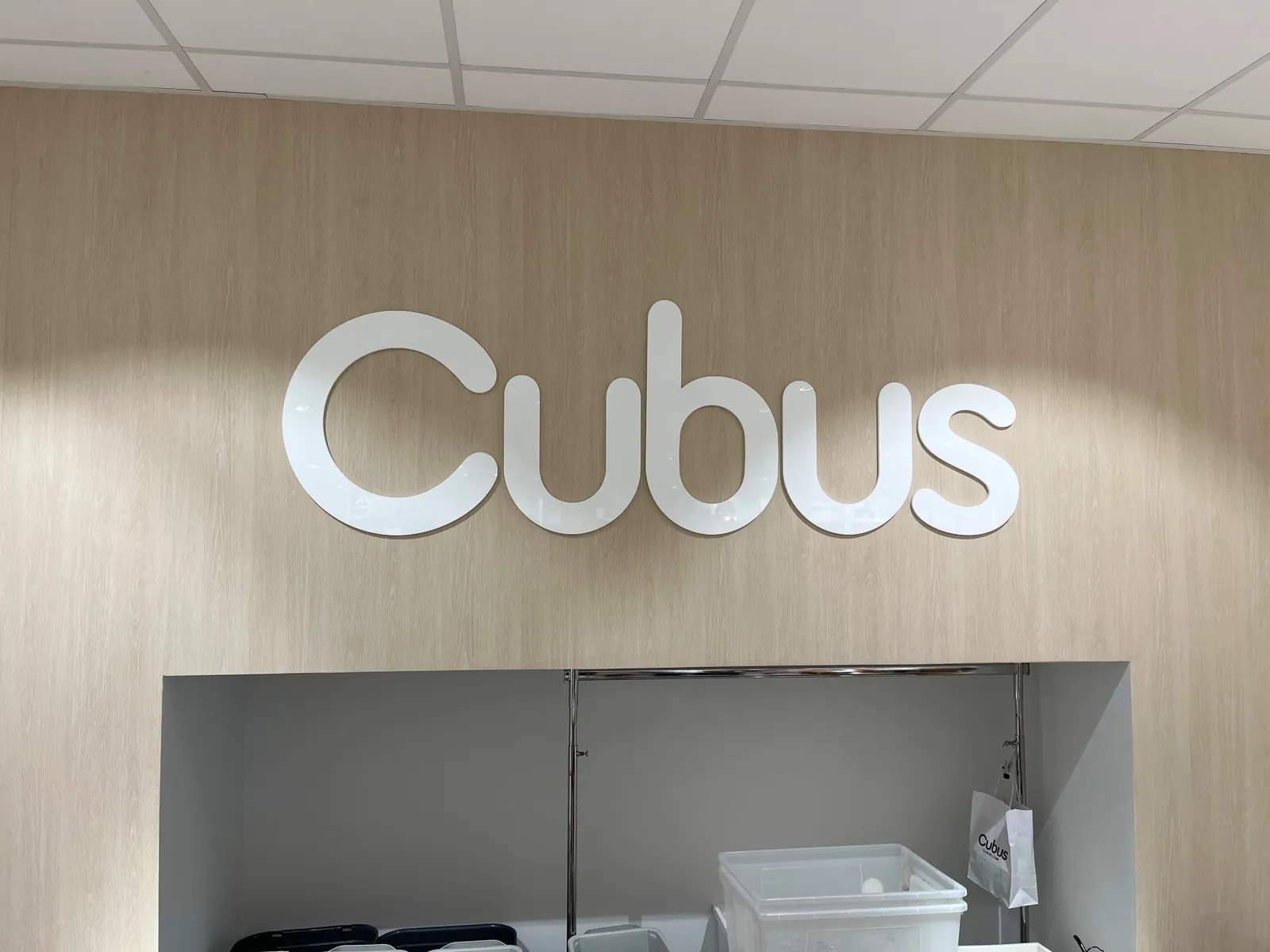 Cubus-logo i utfrest hvit akryl på kassebakveggen i lys eik hos Cubus Holmensenteret