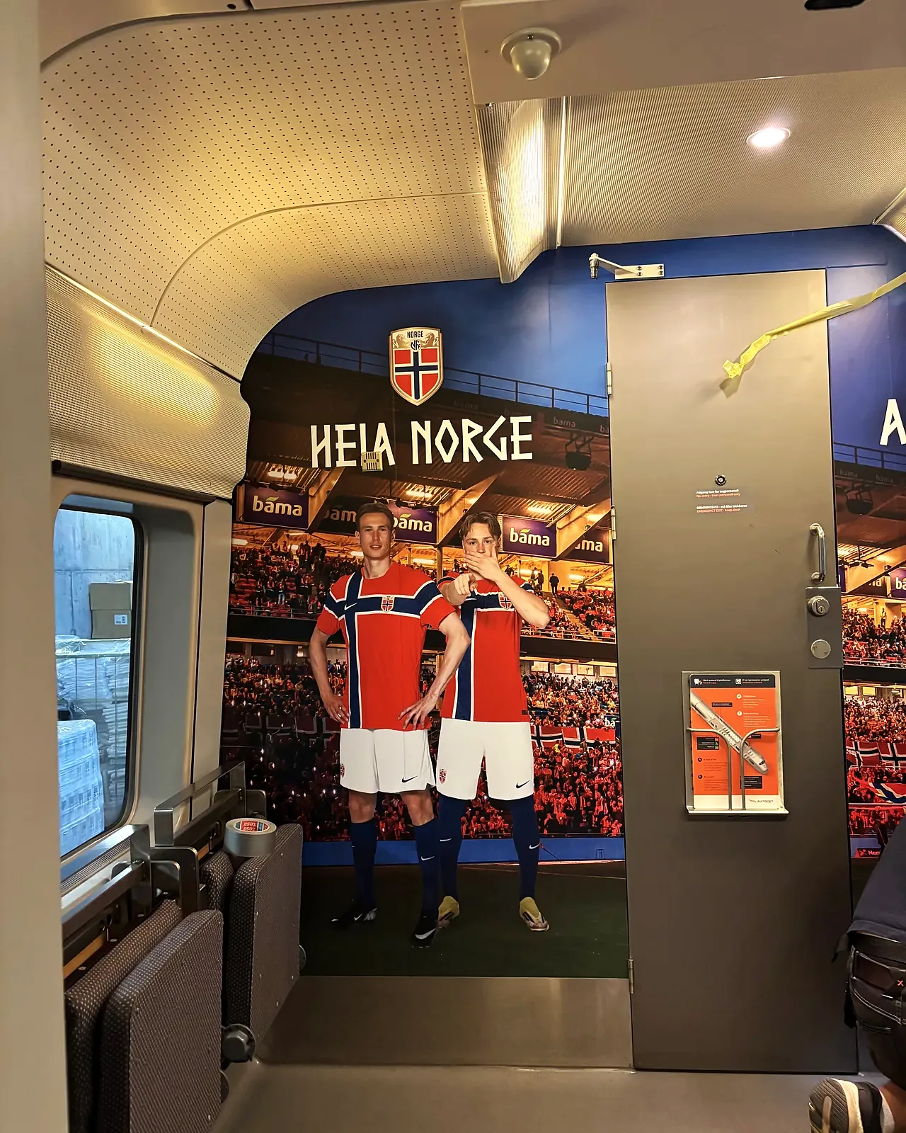 Heia Norge-dekor på veggen bak setene i Flytoget