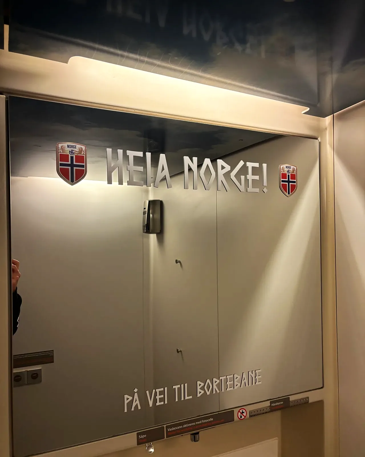 Speil i Flytoget med utskåret tekst Heia Norge og På vei til bortebane