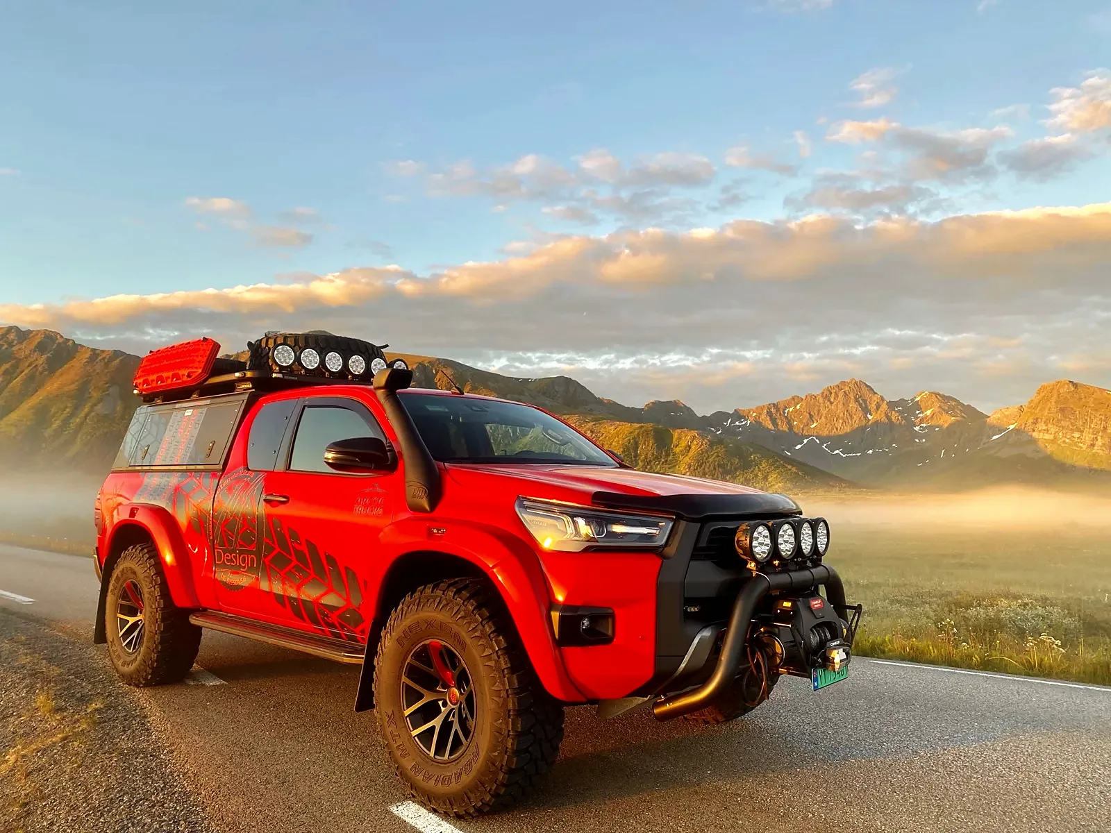 Rød Arctic Trucks Hilux med tidligere dekor på vei i Lofoten