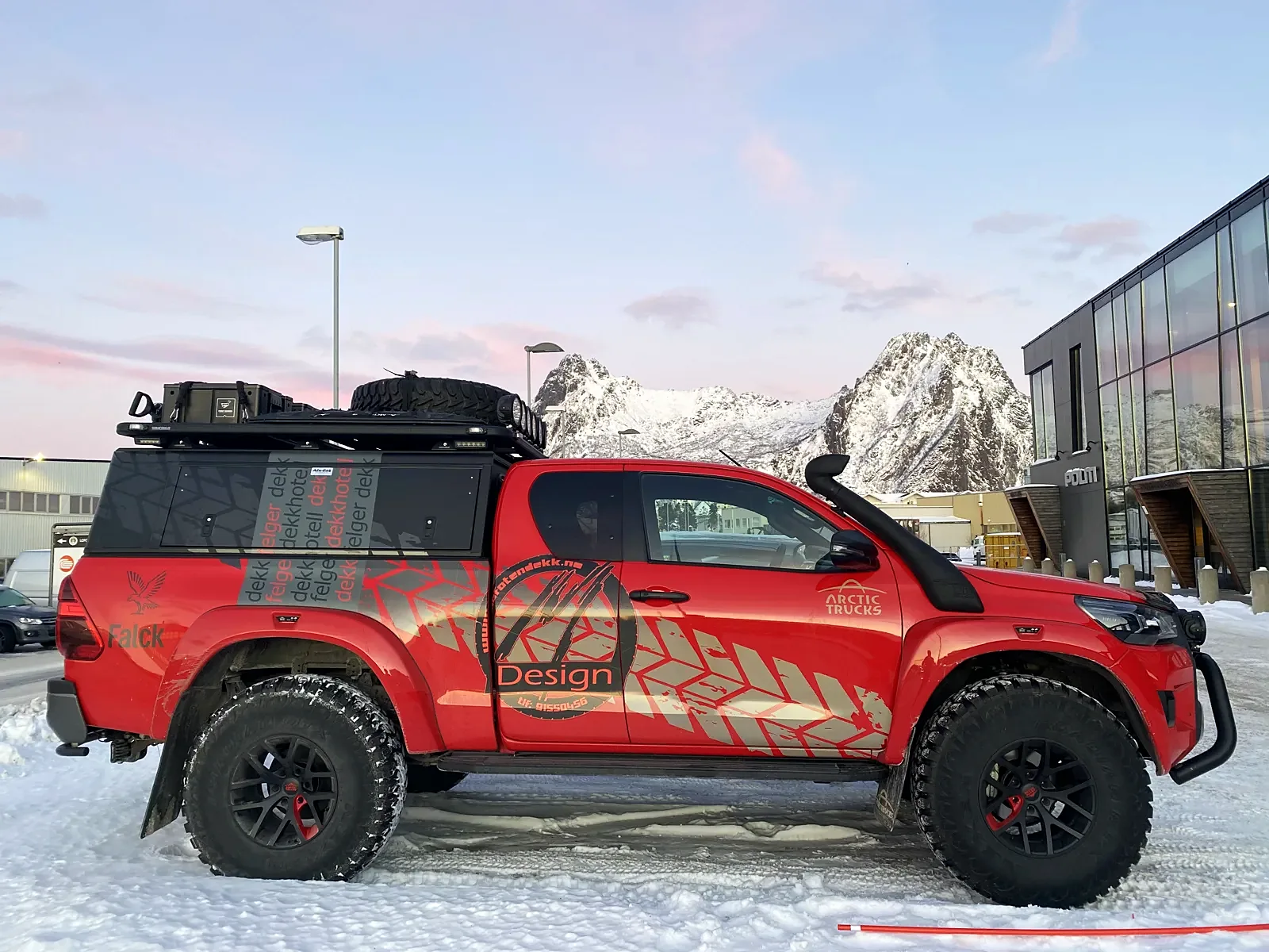Rød Arctic Trucks Hilux fra siden med tidligere dekor
