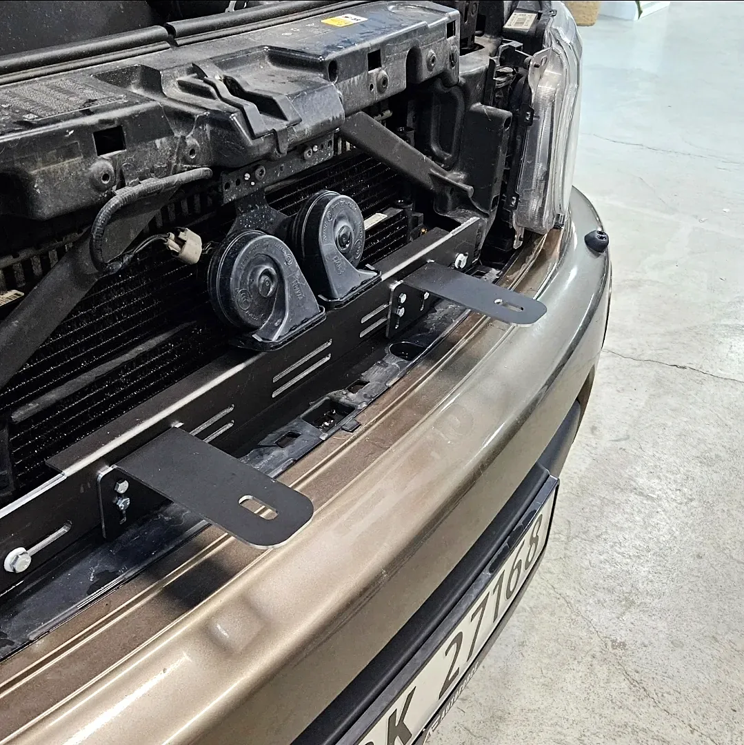 CNC-freste ekstralysholdere i sort aluminium montert bak grillen på Land Rover