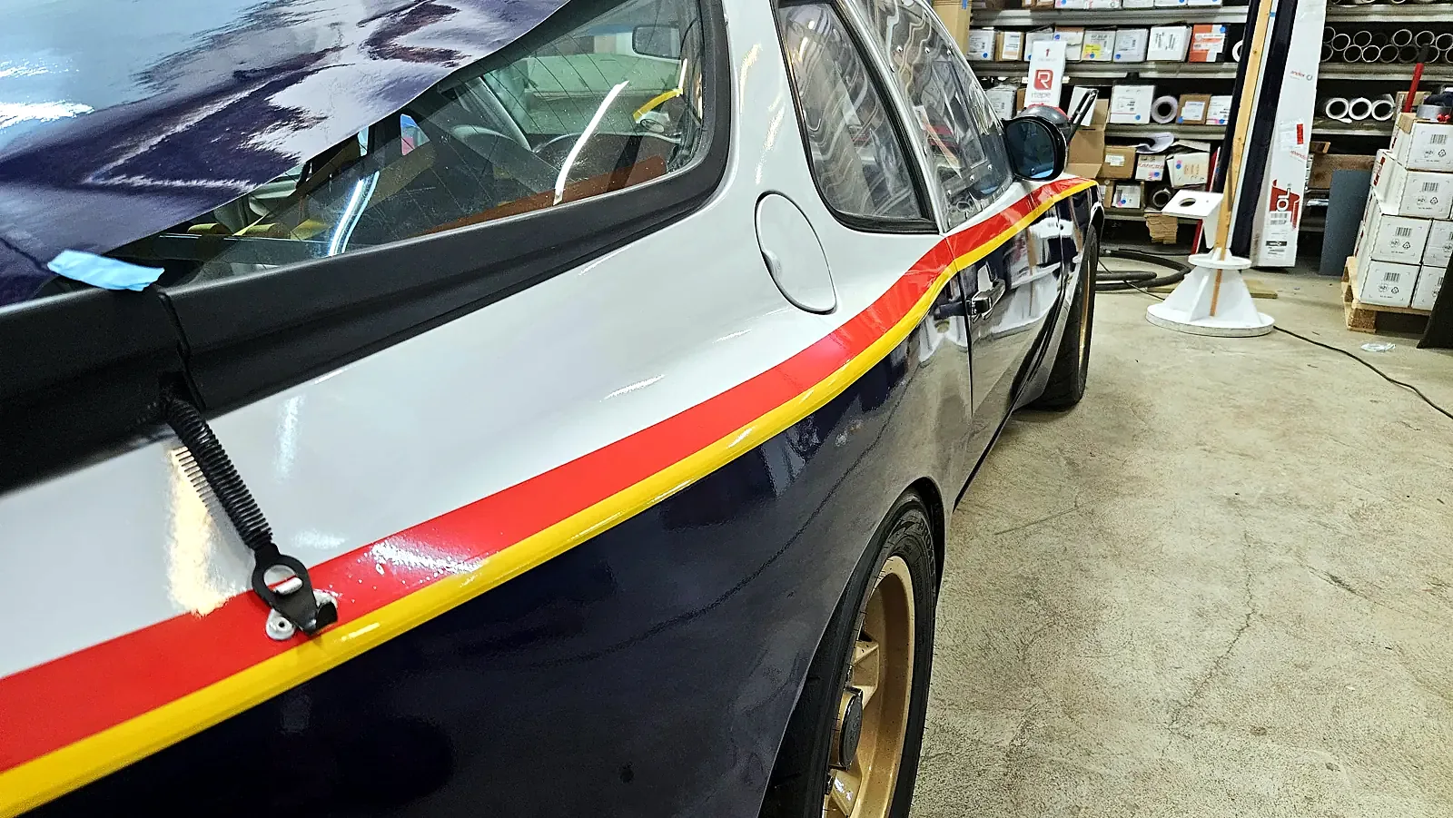 Striper i rødt og gult over bakskjermen på Porsche 944 Cup