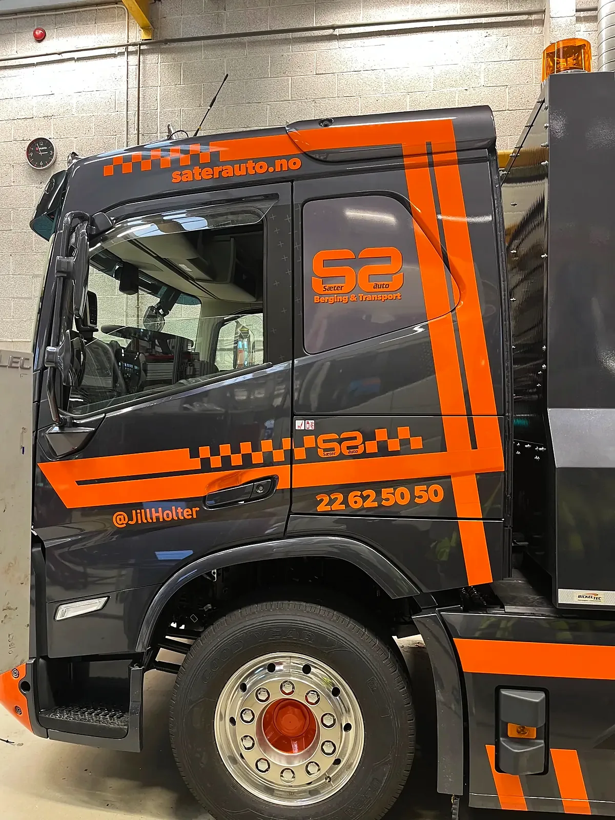 Førerhuset på Sæter Autos Volvo sett skrått forfra, med oransje striper og nettadresse over døra