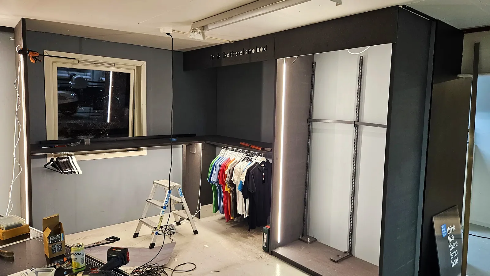 Showroom under montering med lysrammer og klær på plass
