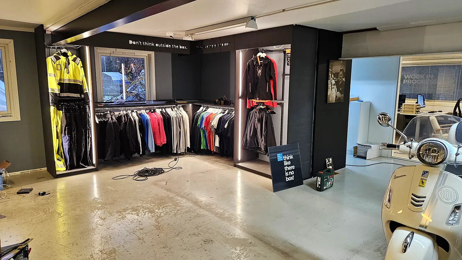 Showroom med arbeidsklær og Vespa under bygging