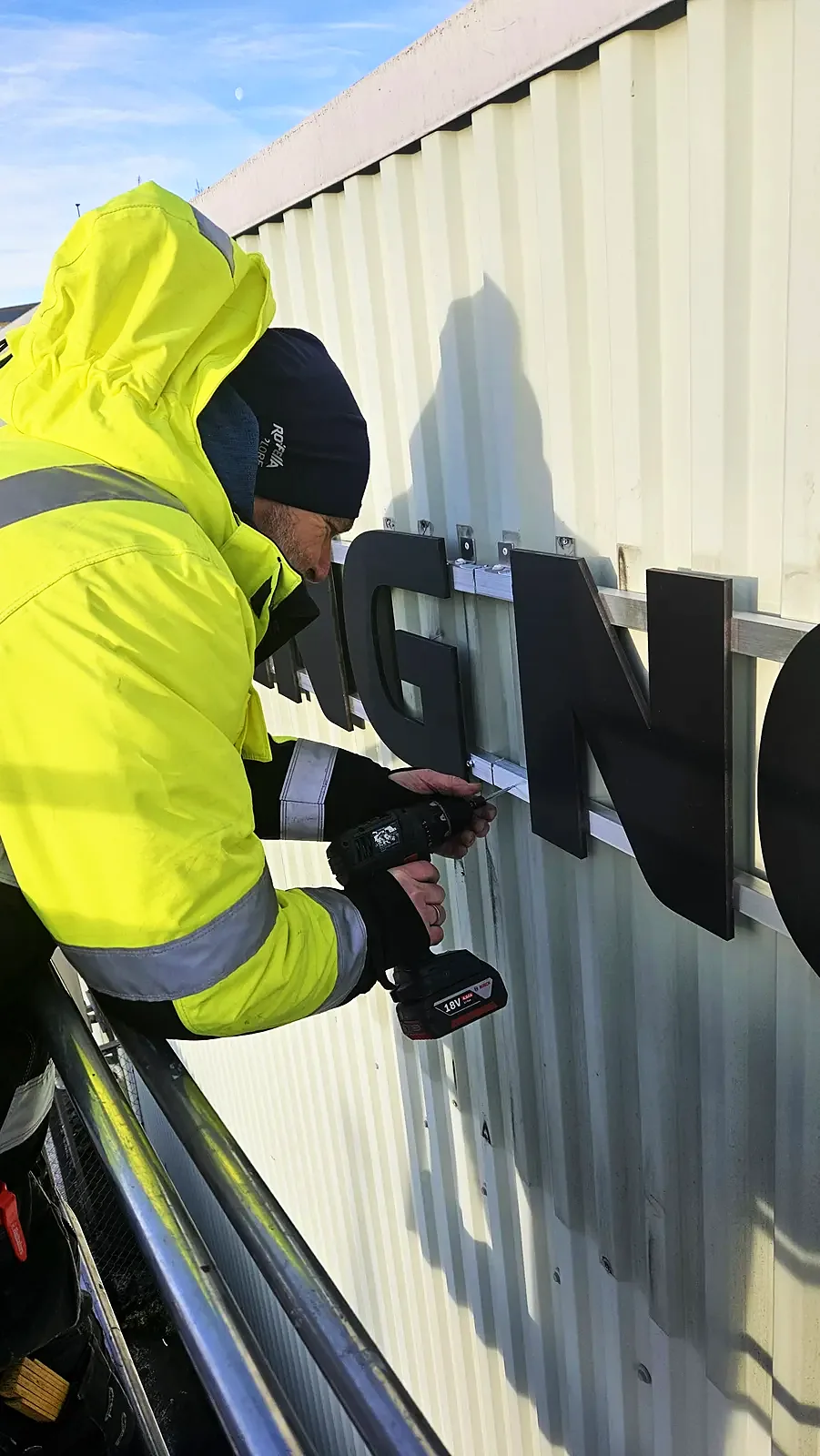 Montør fra Pro Shop monterer skilt på fasaden