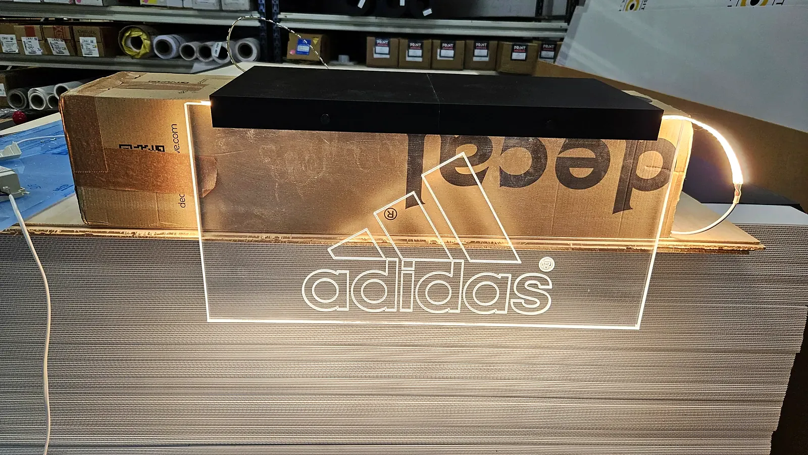 Adidas-logo gravert i akryl med hvitt LED-lys