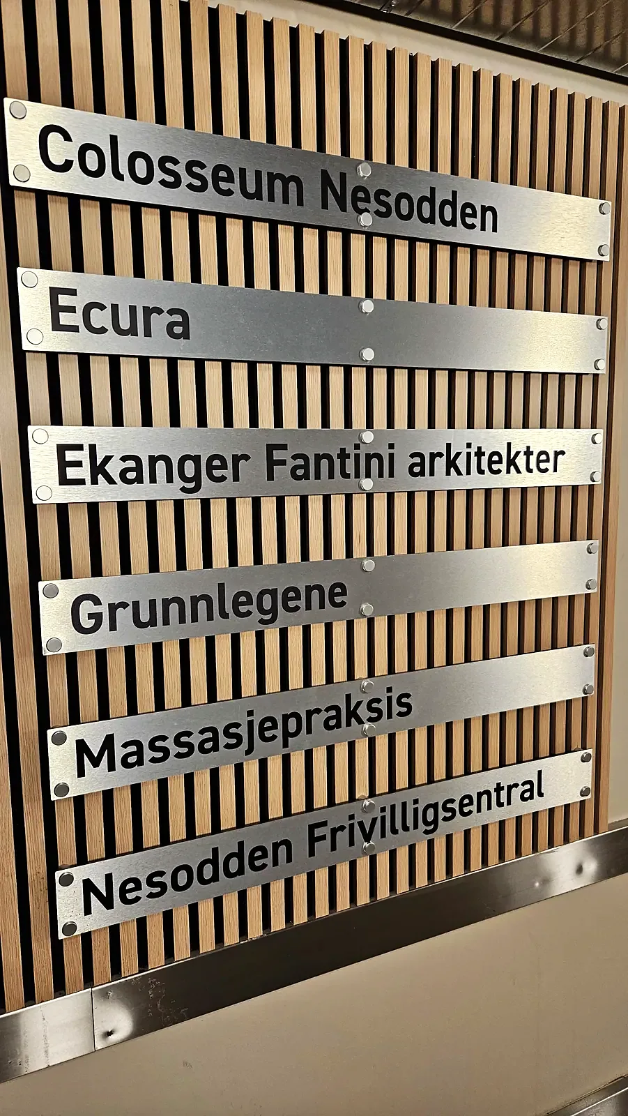 Oversiktsskilt med leietakere i børstet aluminium på trevegg